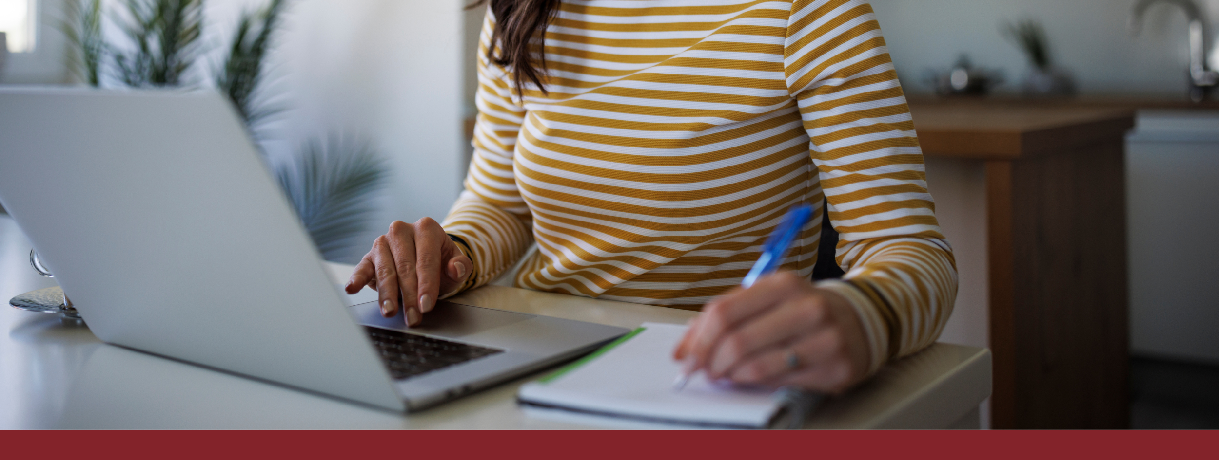 Woman using laptop and writing in notepad
