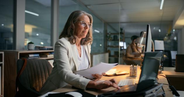 Woman looking at paper and computer