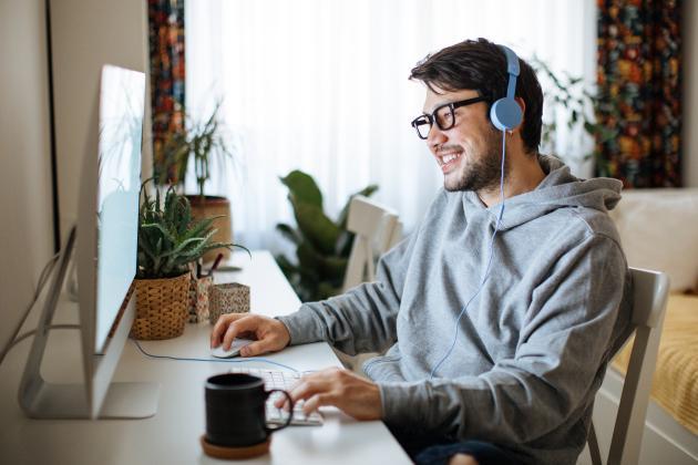 Happy man using headphones as he works on computer