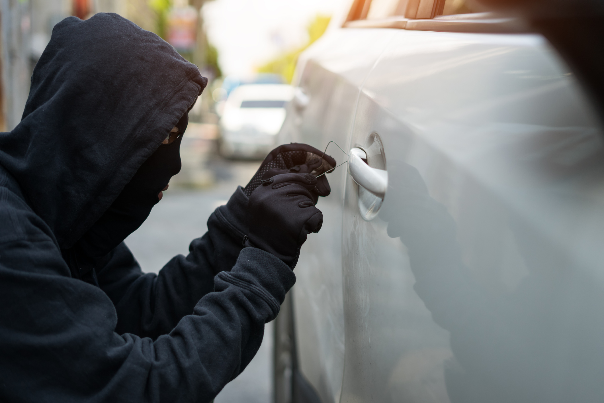 A hooded person breaking in to a vehicle