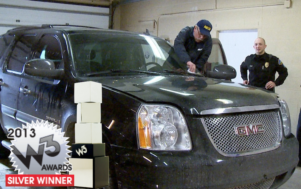 NICB Agent looking at a GMC's windshield