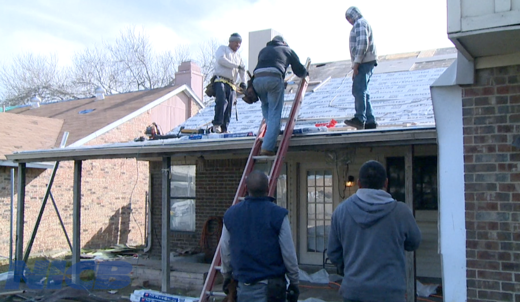 3 men working on a roof while two men are looking on