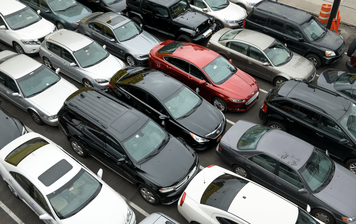 Various cars of different makes and models parked tightly together in a paved lot.