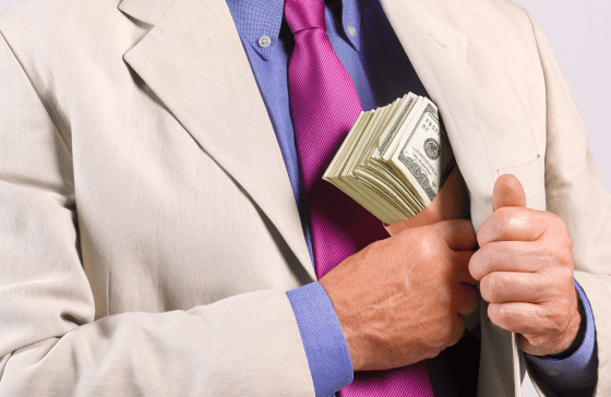 A man in a suit placing cash into his jacket pocket